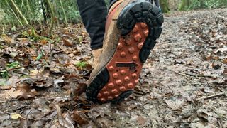 A hiker's foot shoes the sole of the Danner Jag II boots on the trail