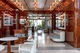 The sleek, wood-drenched interiors of a hotel lobby feature reflective surfaces that expand its retro-inspired allure.