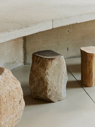 Close up view of a concrete table along with boulder and wooden seats at JIGI Poke restaurant - designed by Vaust studio