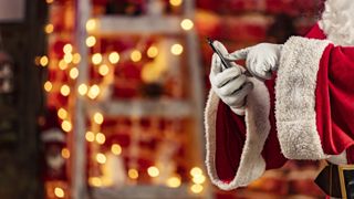 Santa Claus touching a smartphone at christmas at home in the living room