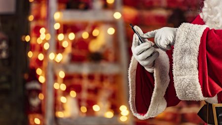 Santa claus touching a smartphone at christmas at home in the living room