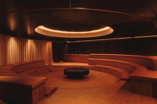 An ingeniously designed spa and sauna features terracotta-drenched, steps-punctuated surfaces, a circular structure, and softly glowing lighting.