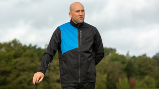 A golfer poses in the Oscar Jacobson Greylands Lightweight Waterproof Jacket