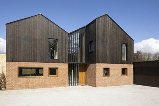 exterior of barn style self build with charred black timber cladding and brick