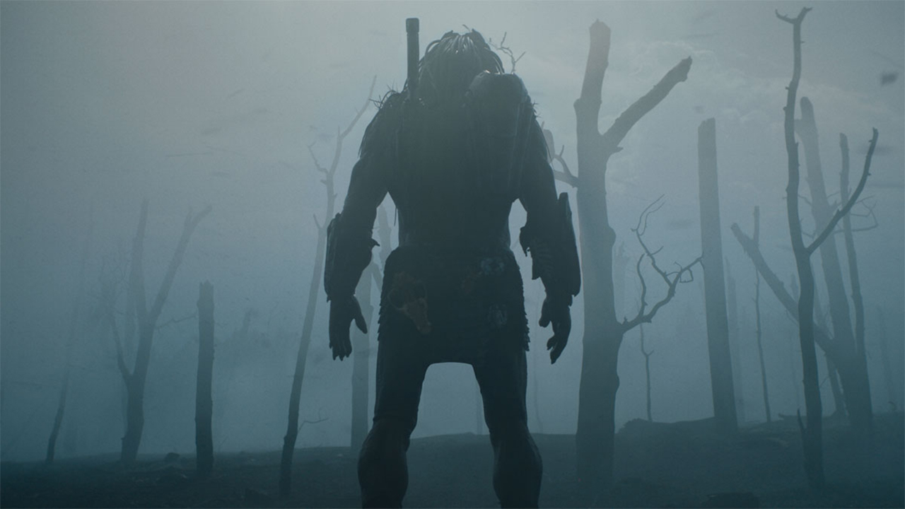 A secen from the new 'Prey' film whereby Predator is standing in the middle of a barren forest which has been engulfed in fog.