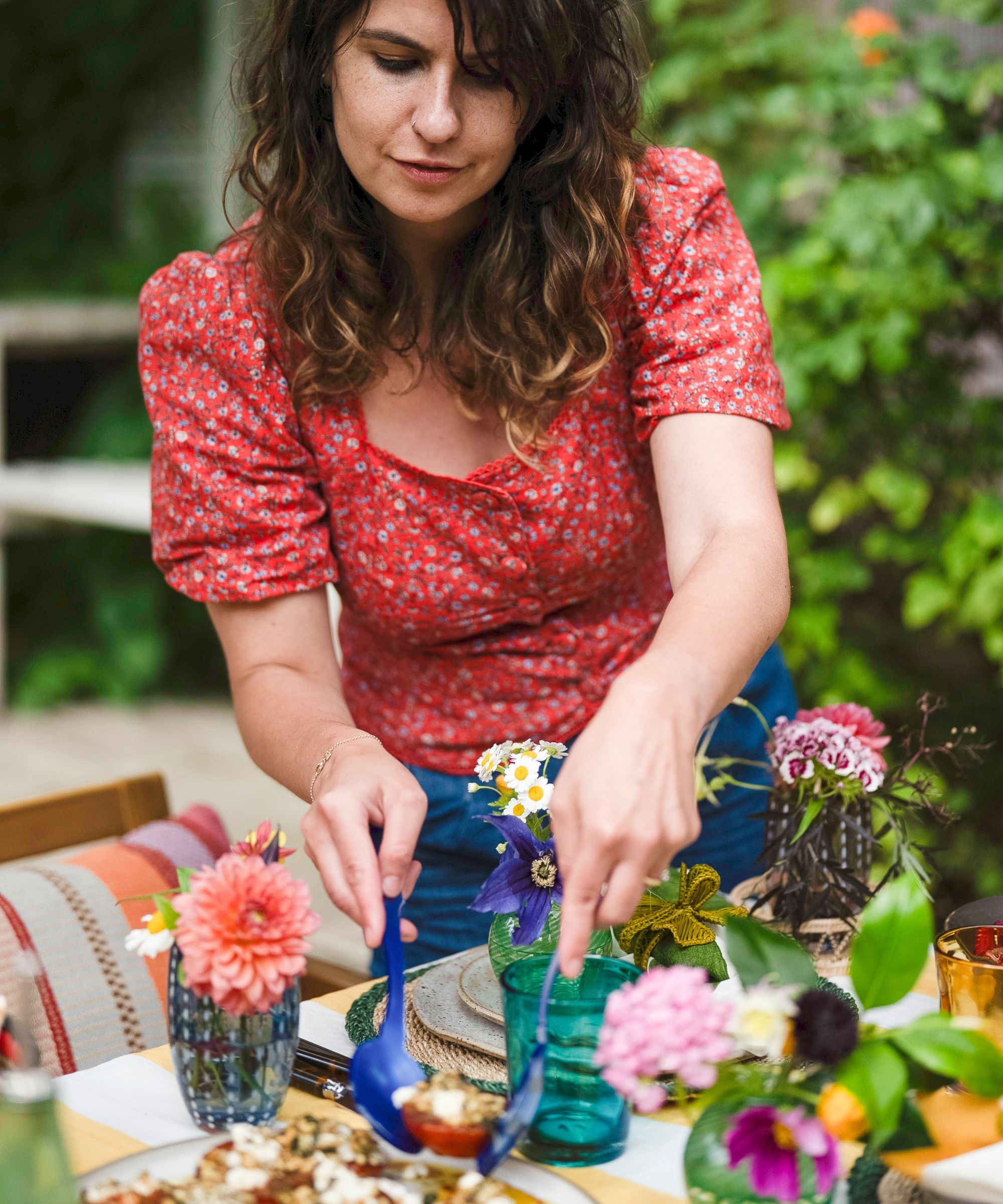 Noor Murad serving food at her summer outdoor table styled with flowers and colorful accessories