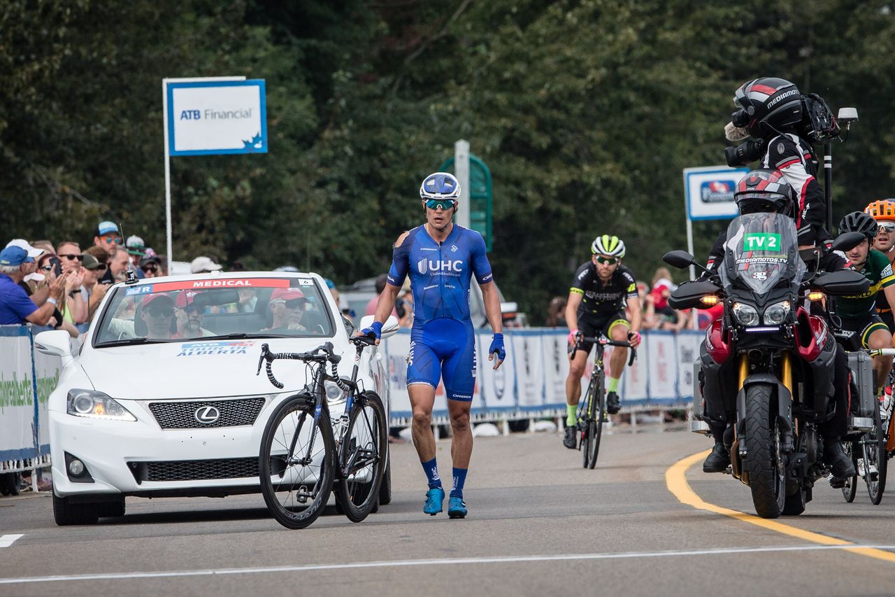 Travis McCabe walks across the finish line after crashing during stage 2 at the Tour of Alberta