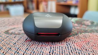 The Edifier NeoBuds Pro charging case on a rug