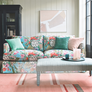 padded blue coffee table footstall with green candle and pink vase