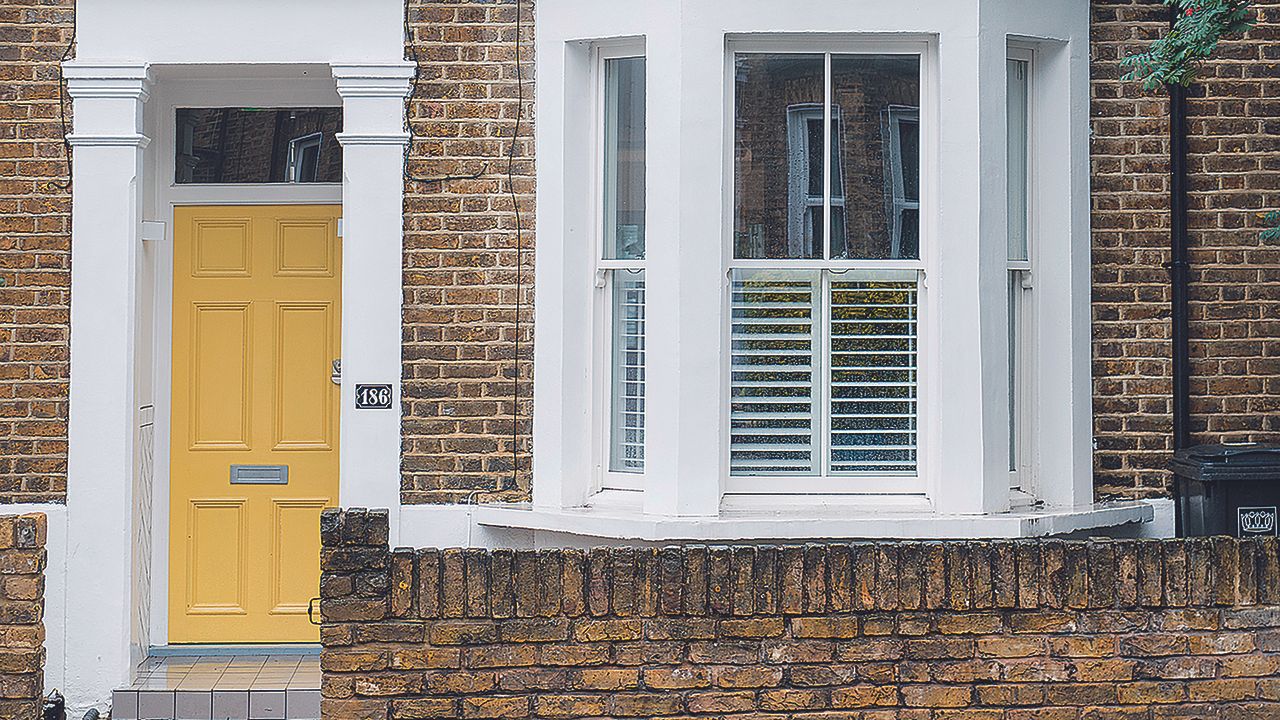 Victorian house with bright yellow front door and bay window.