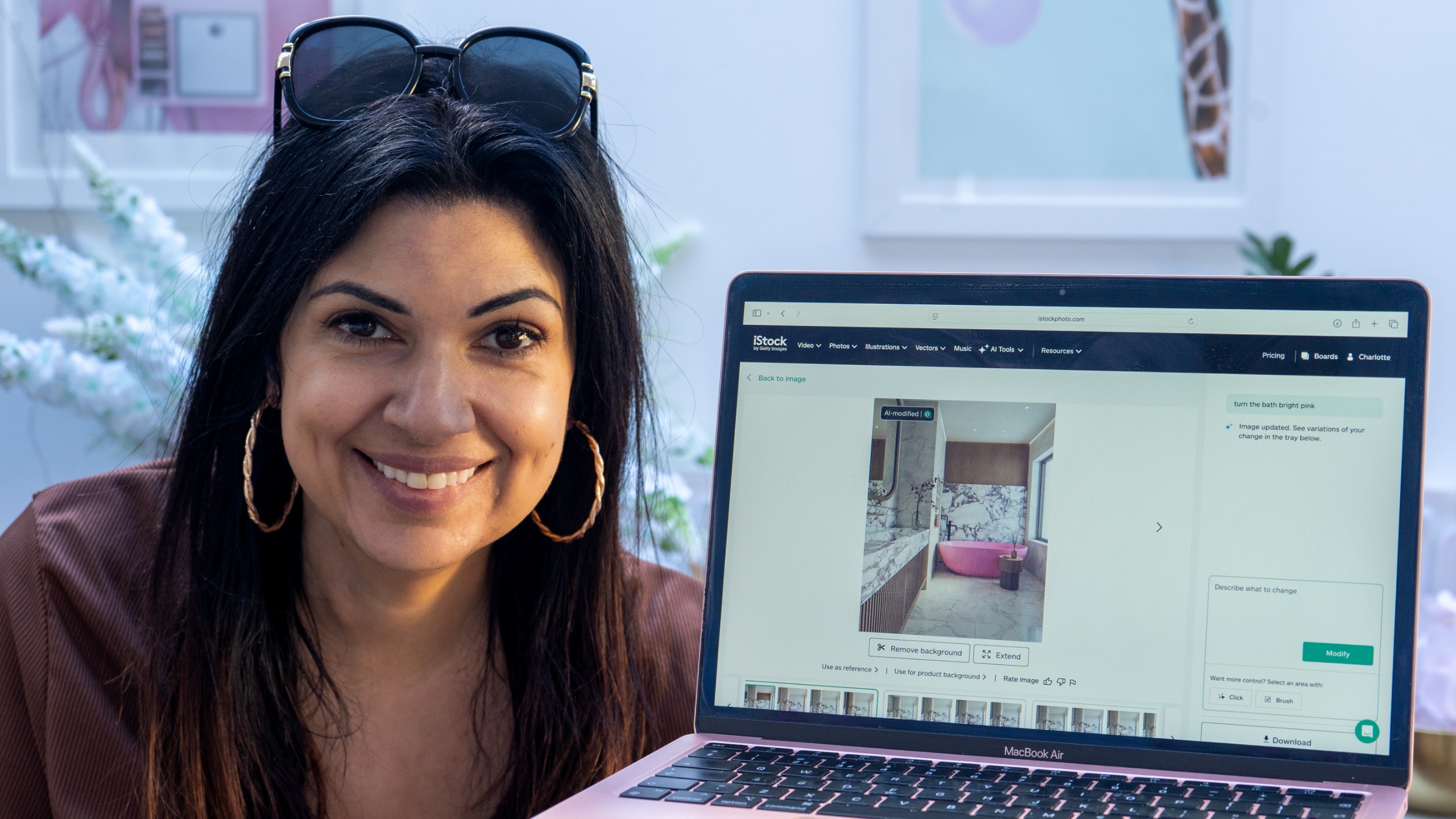 Ariane Sherine Juniper next to a laptop using the iStock AI service to make a hot pink bath image