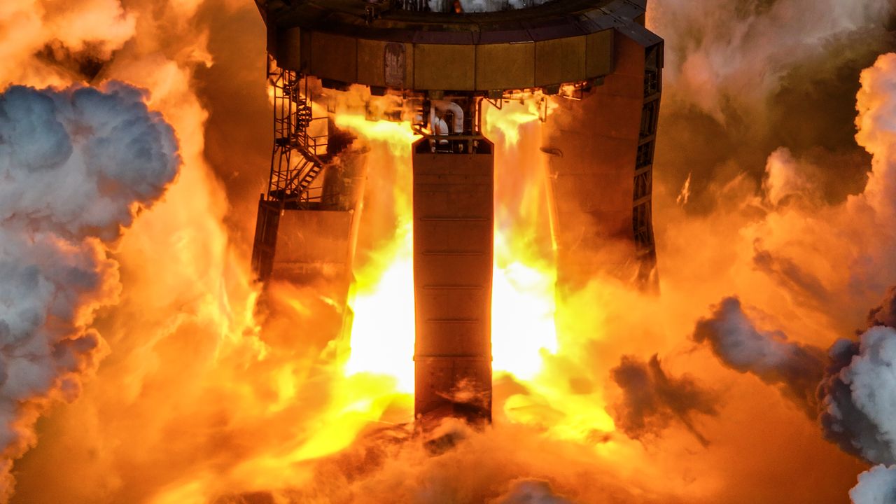fiery smoke envelopes a large test stand, mostly obscured by smoke.