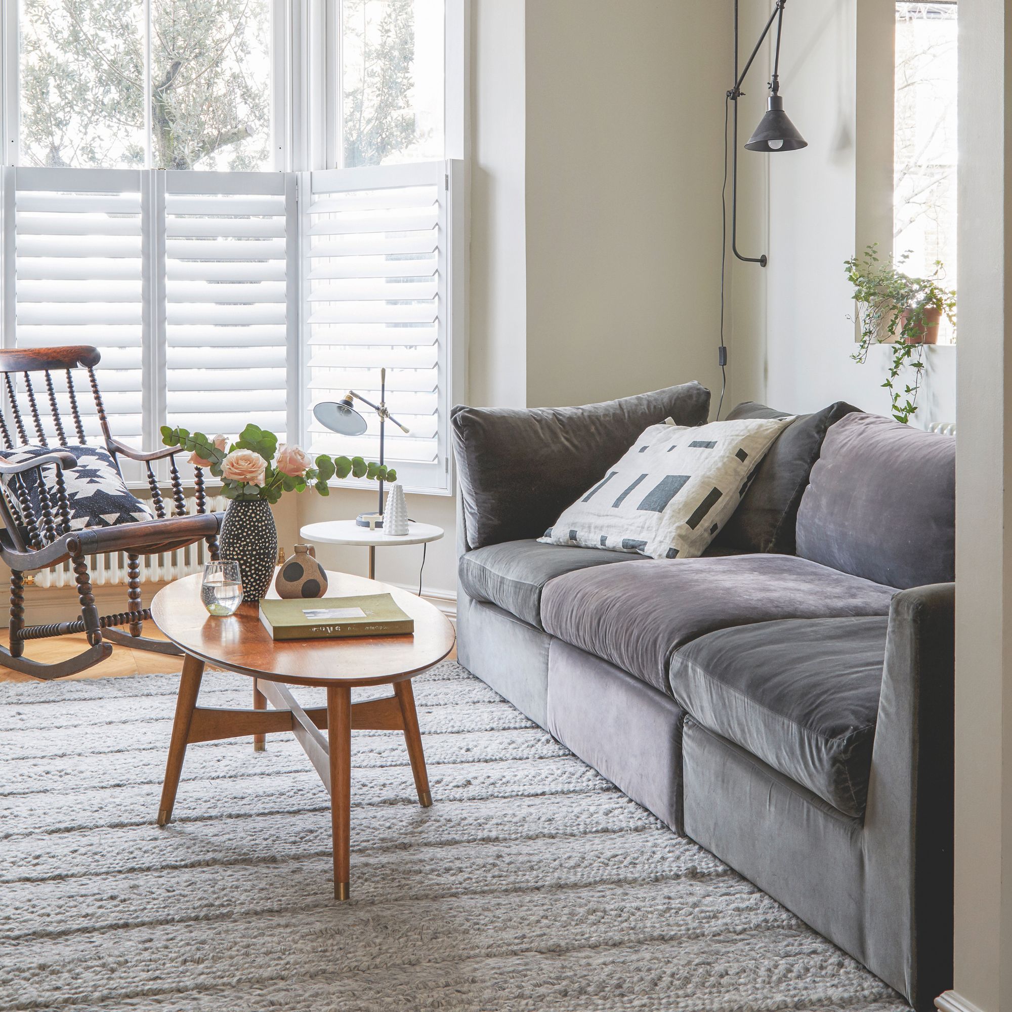 White painted living room with a grey sofa and a wooden coffee table on a rug in the middle of the room