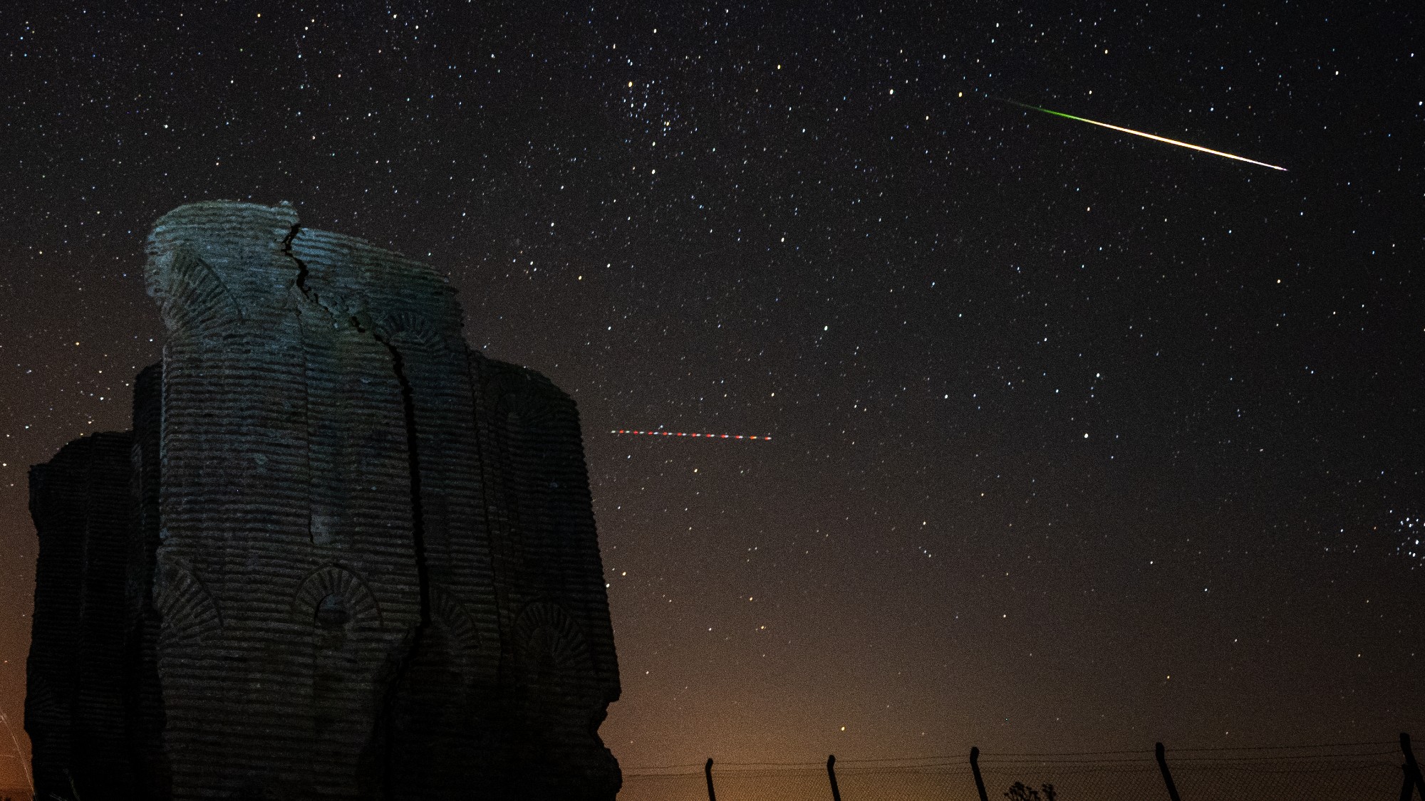 a streak of light crosses through the night sky