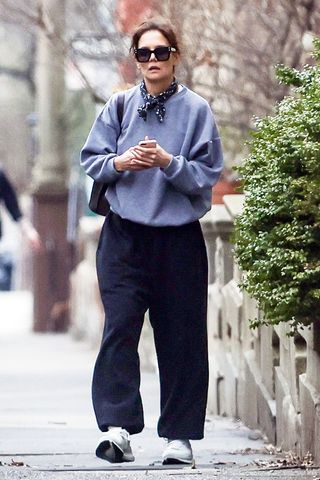 Katie Holmes wearing a sweatshirt, black pants, and sneakers.