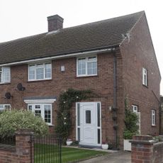 exterior of a red brick period house with driveway and white front door