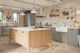 A pale green kitchen with a wooden tongue and groove island in the middle of the room