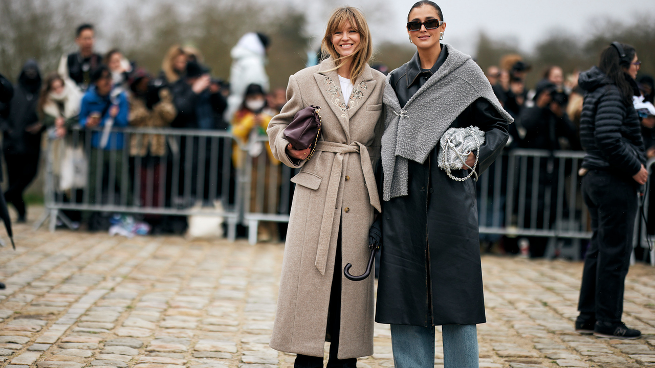 two guests attend paris fashion week spring summer 2025 wearing beige and grey coats holding bags 