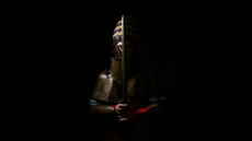 A man wearing a replica suit of armor that includes a helmet and sword.