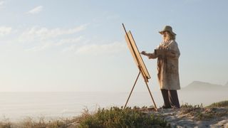 A lady paints an outdoor landscape