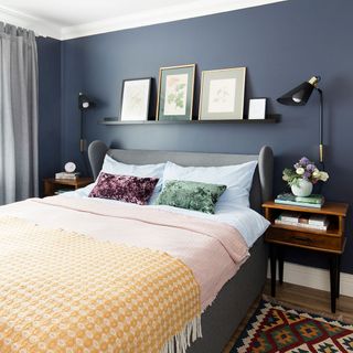 master bedroom with blue wall bed with designed cushion and frames on wall shelf