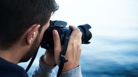 A man using one of the best DSLR cameras next to lake