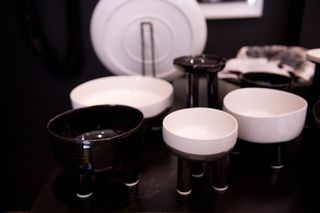 White and black ceramic bowls nd plates on display, photographed against a black background on a black surface