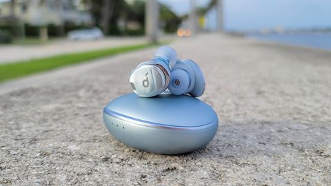 The Anker Soundcore Liberty 3 Pro on display against a backdrop of a coastal street with palm trees