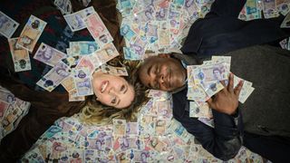 Janet and Samuel lying in a pile of bank notes in Boat Story episode 3