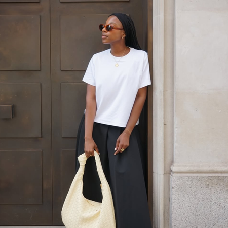 Taffy in white T-shirt, woven bag and culottes.