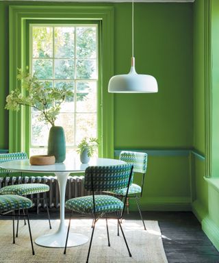 Green painted dining room with green table and hanging light