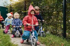 Children using scooters in garden of a nursery