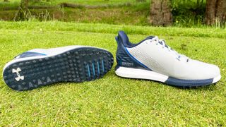 The outsole and profile of the Under Armour HOVR Drive 2 SL shoe as shown on a golf tee box