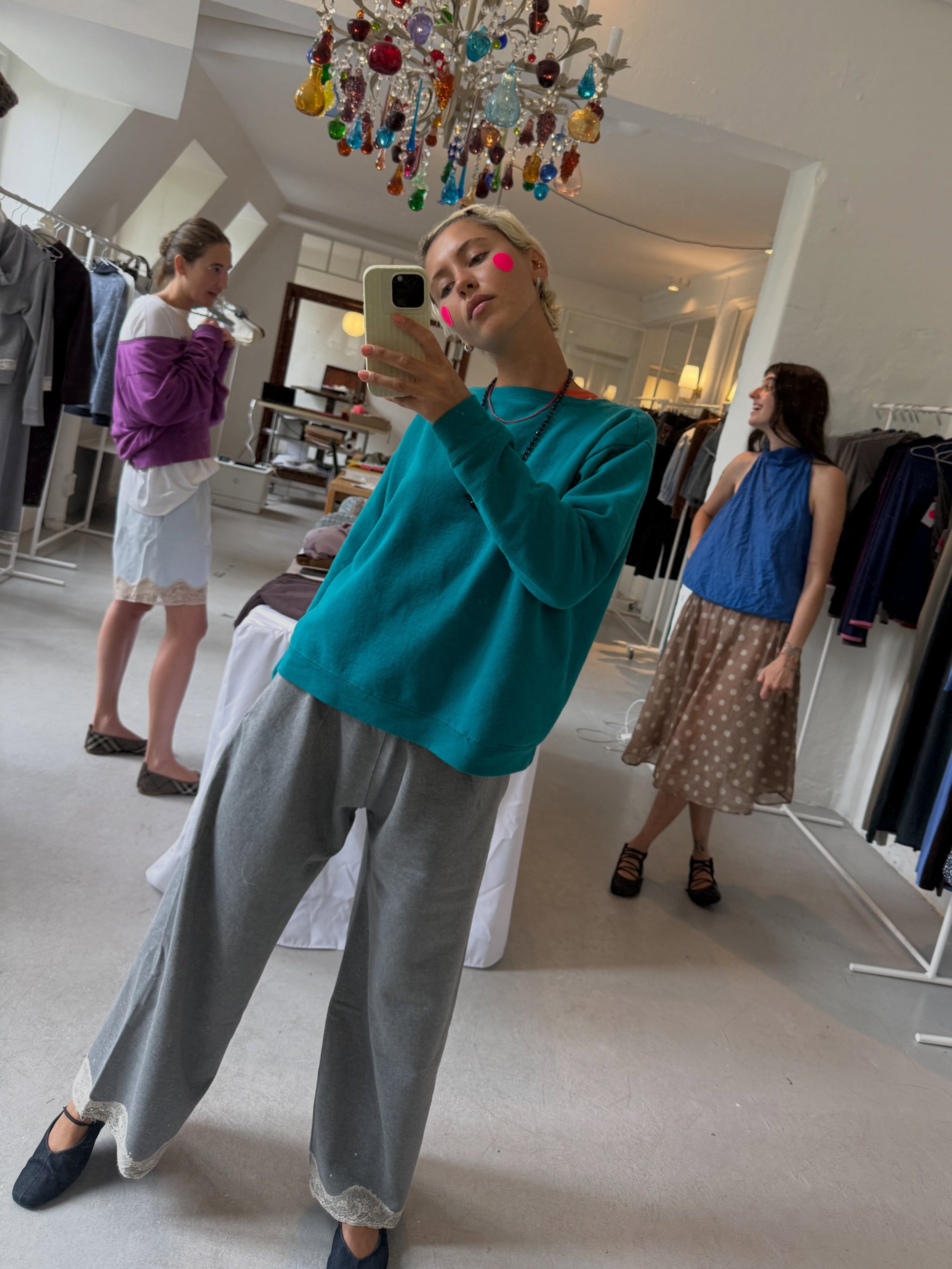 Iris Law takes a mirror selfie wearing grey lace-trim trousers with ballet flat mary janes and a teal knit.