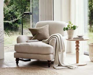 The White Company Petersham Linen Union Armchair in netural, bright home beside a side table and jute rug with a blanket