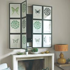 A living room with a TV placed above the fireplace and concealed with fold-away artwork