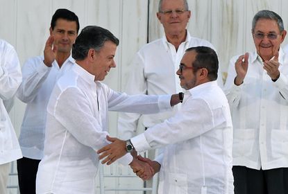 Colombian President Juan Manuel Santos and FARC rebel leader Rodrigo Londono Echeverri shake hands.