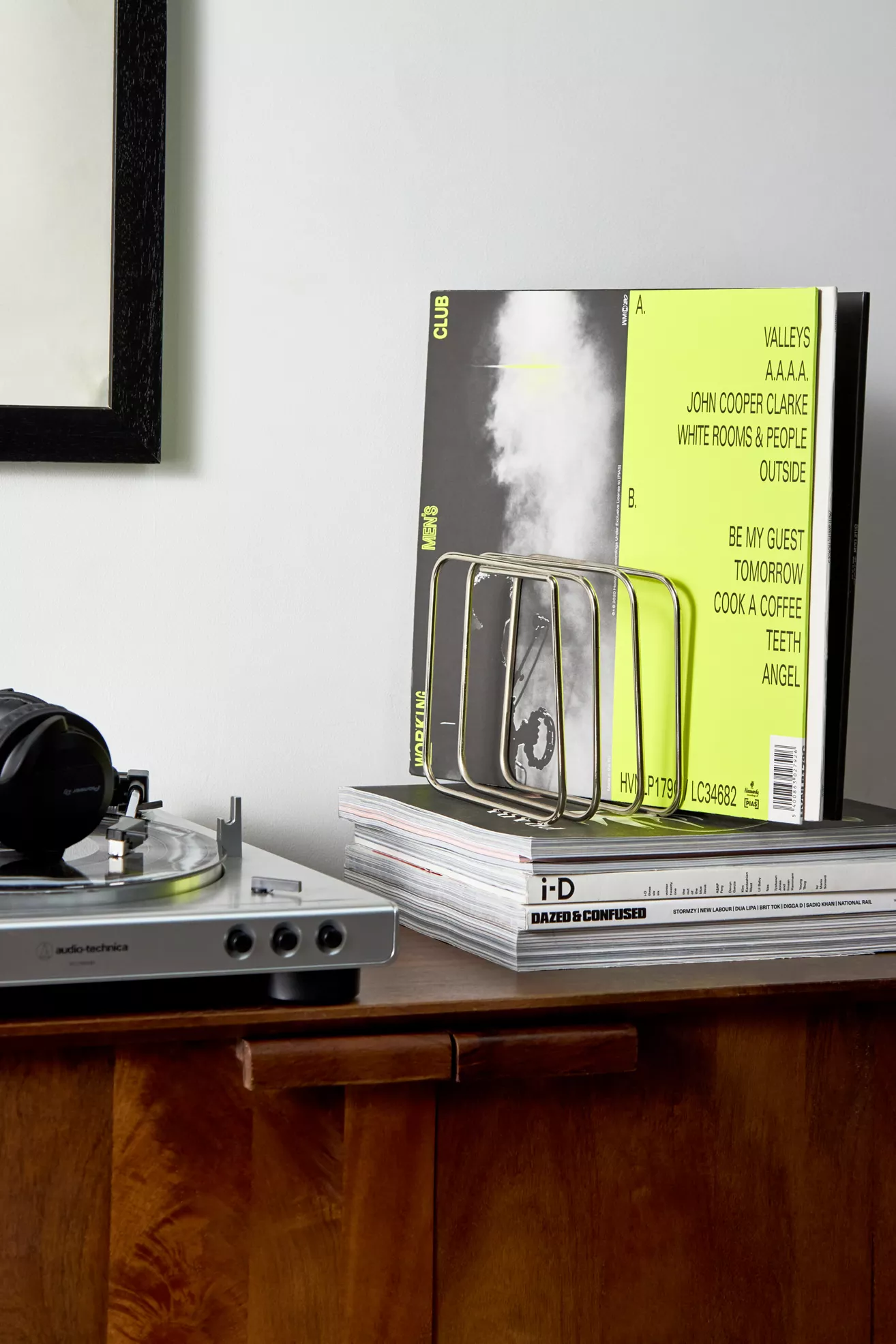 Cube Vinyl Storage Rack with a neon green vinyl in it on a stack of magazines.