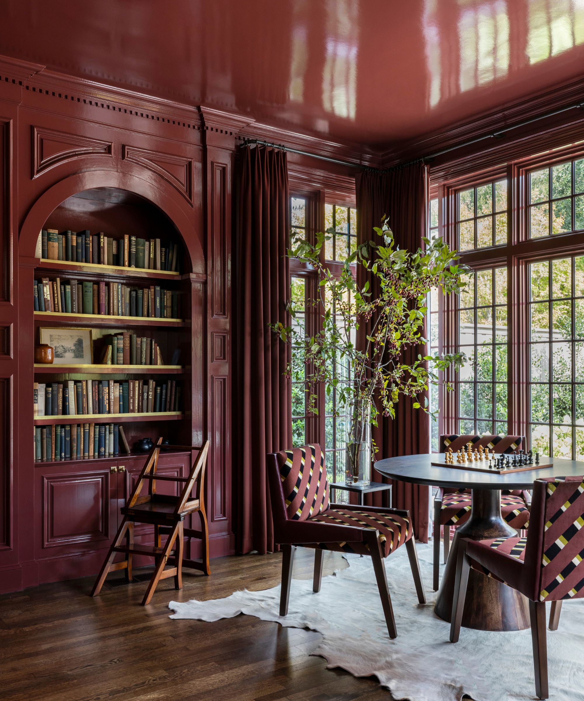 dark cherry red color-drenched library room with large windows, walls, built-ins and ceiling in gloss finish