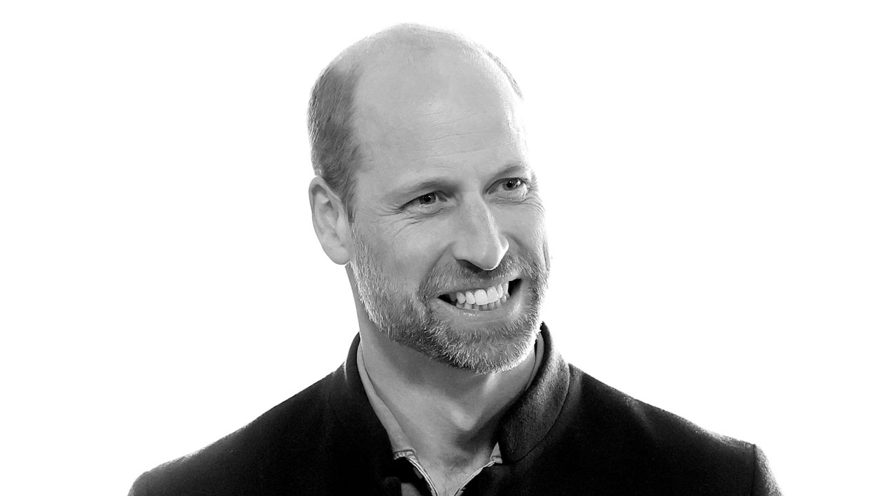 A black and white headshot photo of Prince William smiling and wearing a dark jacket