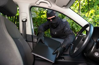 Thief stealing laptop from car