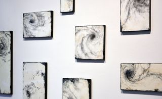 Photos on a white wall at an exhibition by Yamamoto