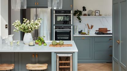 A blue kitchen with a marble backsplash