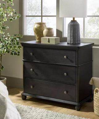 A black dresser in a neutral-toned bedroom