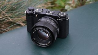 Fujifilm X-M5 camera with a Fujifilm 35mm lens attached on a green surface