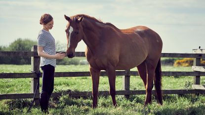 Woman with partially sighted horse in the field