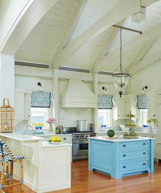 kitchen with white walls high shiplapped ceilings and blue island with cream cabinets