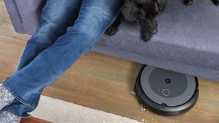 iRobot Roomba i3 robot vacuum cleaning underneath a piece of furniture