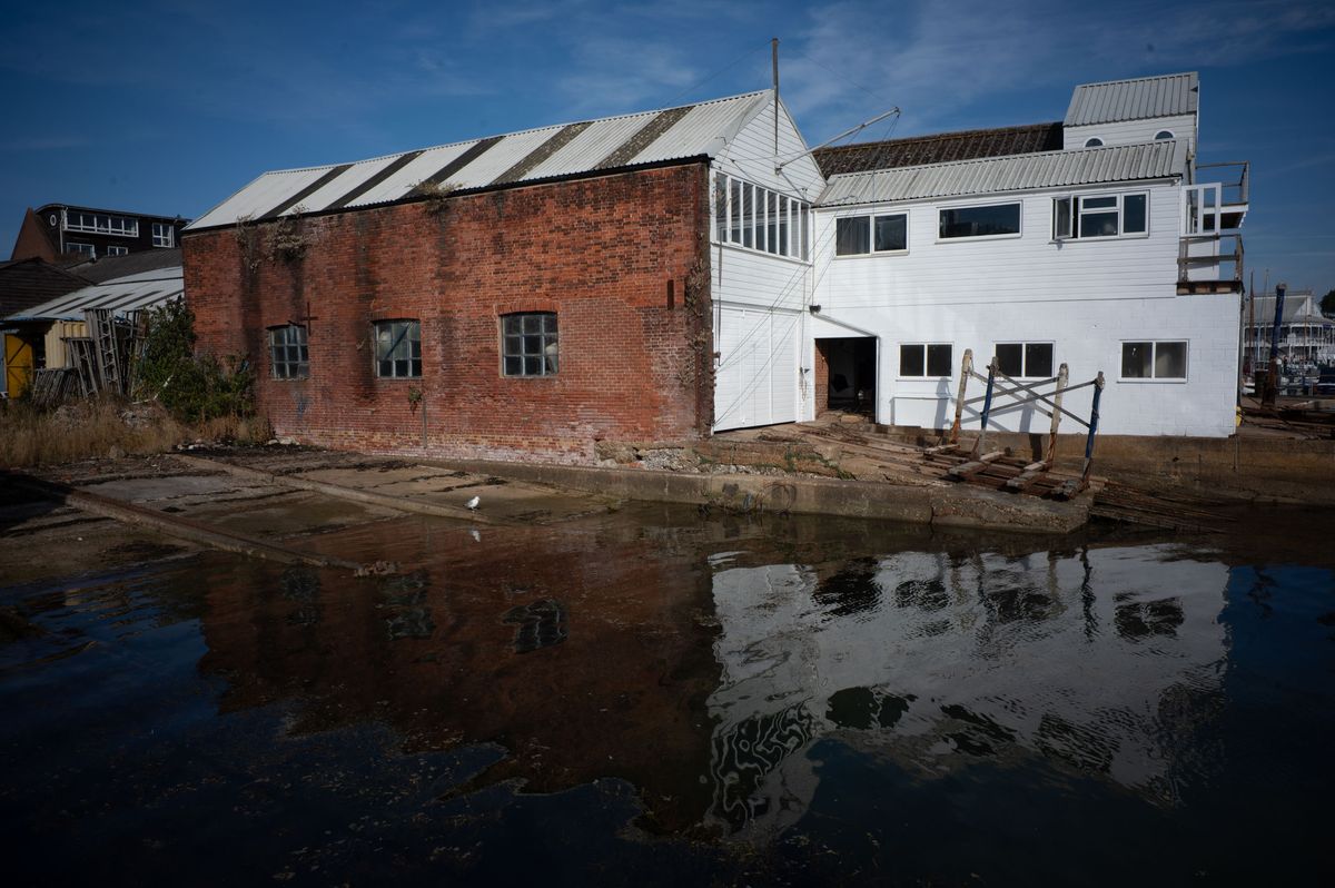 Dockside industrial building, reflected in still clear water on a sunny day