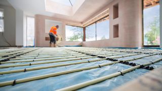 Underfloor heating system being installed in a modern home with large windows and a skylight, ready for screed and final floor finish.